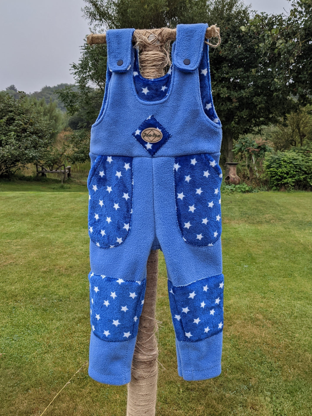 Kid's fleece dungarees in sky blue with blue stars.
